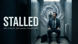 Stalled kısa film afişi: Tuvalet kabininde zaman döngüsüne sıkışmış bir adam ve zaman tüneli görseli. Stalled kısa film afişi: Tuvalet kabininde zaman döngüsüne sıkışmış bir adam ve zaman tüneli görseli.